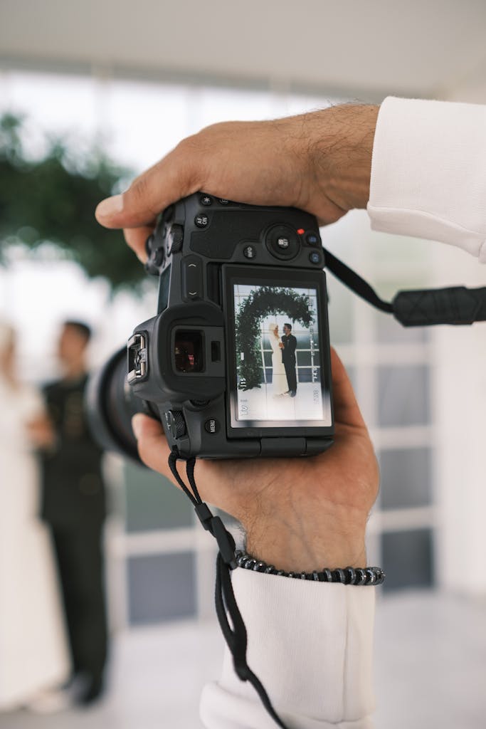 A wedding photographer captures a couple's joyful moment through the camera's viewfinder.
